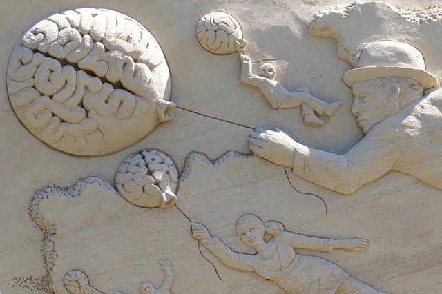 Sand sculpture of people with brain balloons