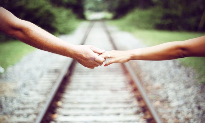 Image of a man and a woman holding hands over a railway track