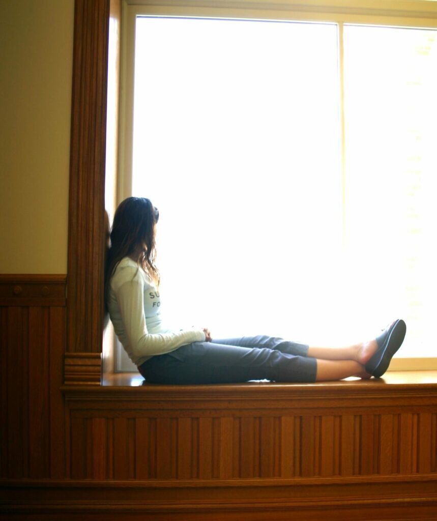 A woman sits alone and looks out of the window
