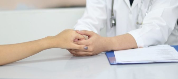A doctor holds a patient's hand