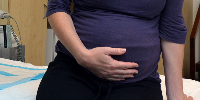 A pregnant woman clutches her stomach