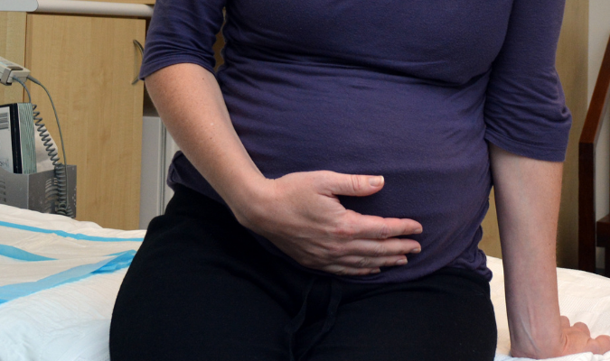 A pregnant woman clutches her stomach