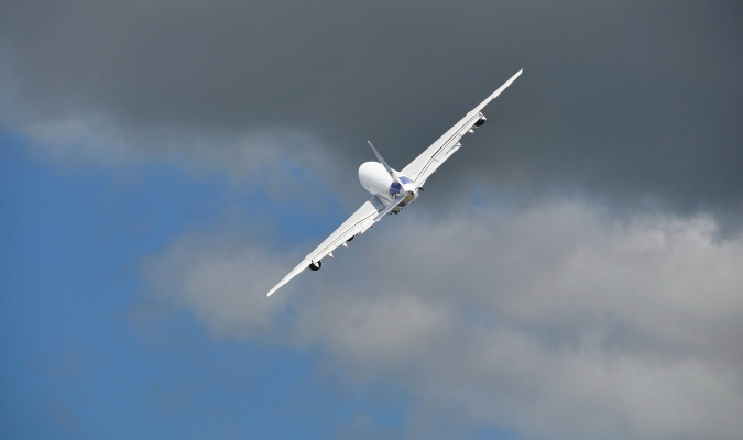 An airliner banks against grey cloud