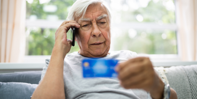 An elderly man on the phone holding his credit card