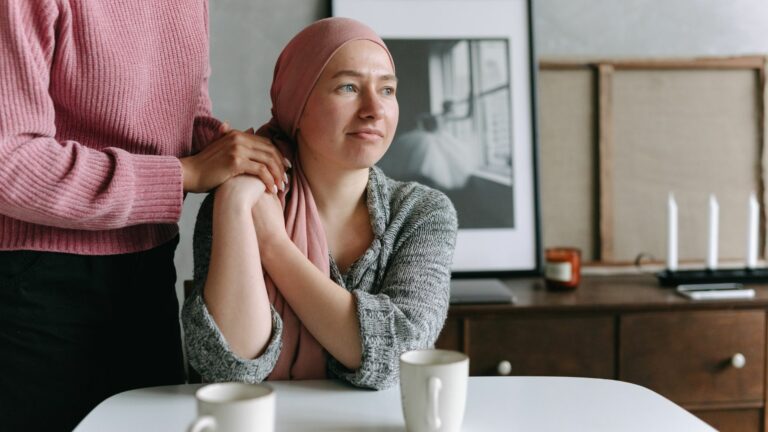 Woman with cancer holding hands with friend