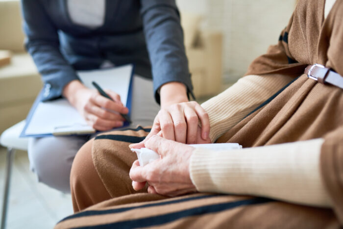 Close up of female psychologist holding hand of senior woman