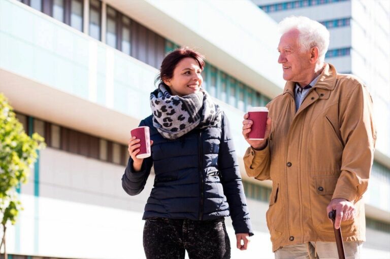 Two people walk side by side with takeaway coffee cups