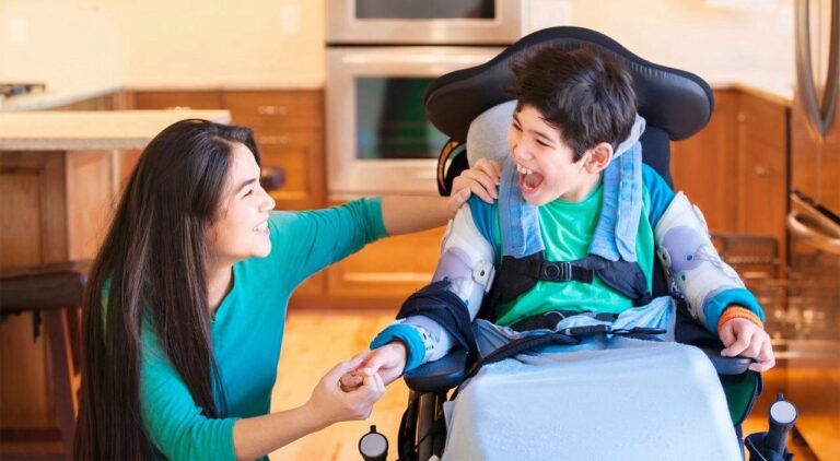 A woman laughs with her son in a wheelchair
