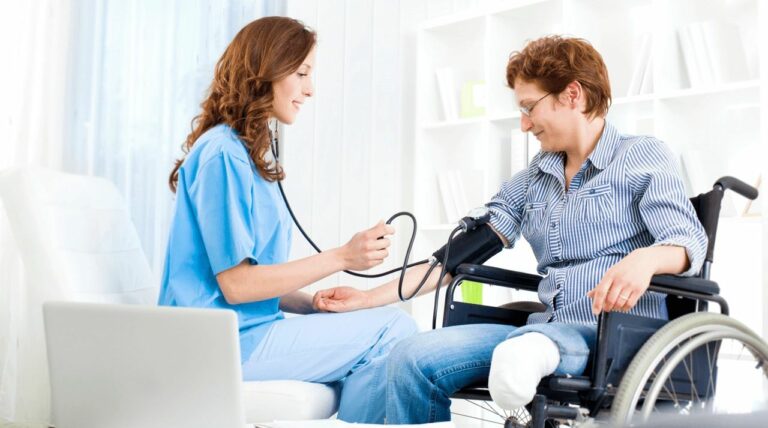 A doctor takes the blood pressure of a person in a wheelchair