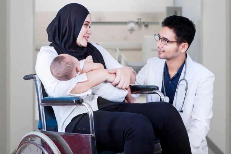 A woman holds her baby while talking to a doctor
