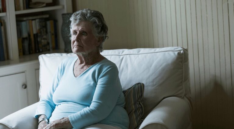 An older lady sits in an armchair