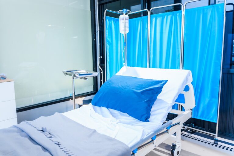 An,Empty,Medical,Bed,Sits,In,A,Glass,Hospital,Room,