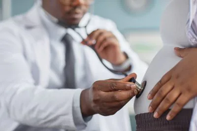 Black,Male,Doctor,Examining,Pregnant,Black,Woman,By,Listening,To